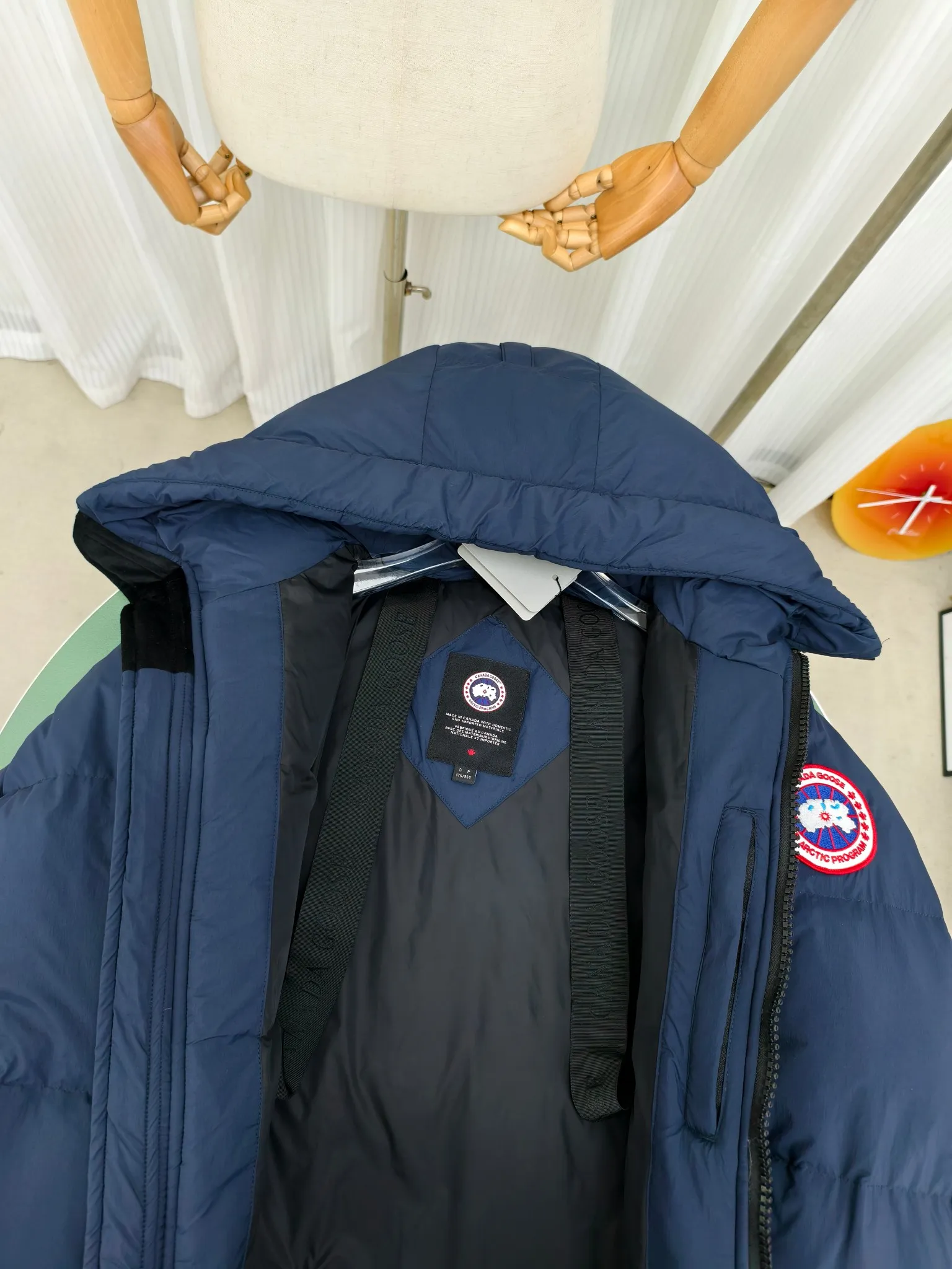 P940 Canada Goose Lawrence Down Jacket The Lawrence Down Jacket provides essential protection for everyday adventures and is made from sustainable Enduraluxe fabric with a durable soft touch. It features a quilted body, an adjustable down hood and a longer hem. Adjustable, down-filled, communicated hood. Two-way center front zipper increases range of motion and ventilation. The chin-protecting suede knit stand-up collar is soft and extra-comfortable. Inset rib-knit cuffs for added comfort and locked in heat. CORDURAD piping at the cuffs hem and reflective double-stripe grip tape at the back. Internal shoulder strap Color: black with red label black with black label azure blue Size: XS-2XL